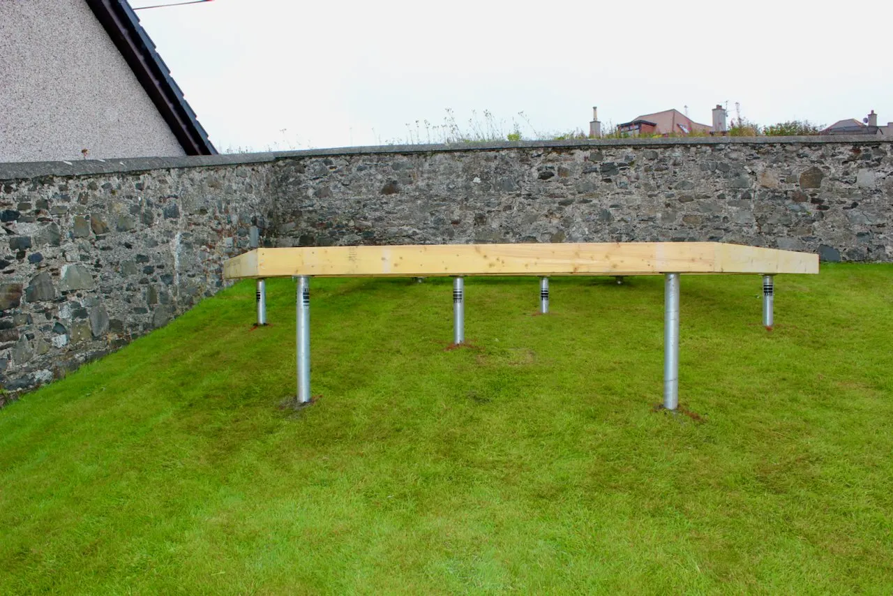 A timber garden deck raised on galvanised ground screws over a level lawn